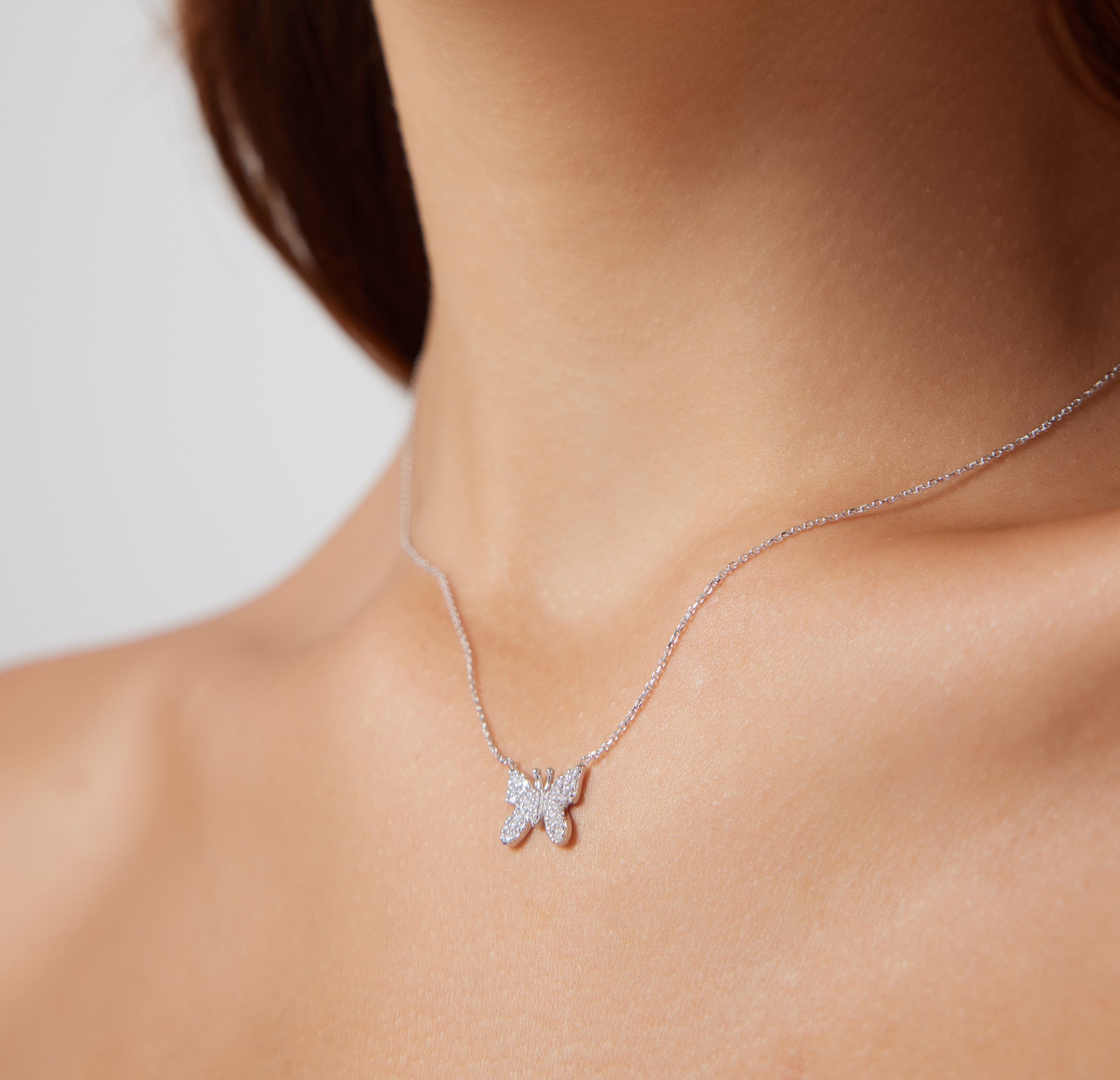 14K solid white gold butterfly necklace with diamonds showcased on a model's neck, elegant and sparkling design.