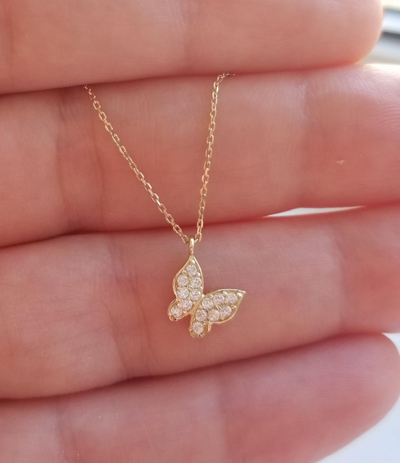 14K solid yellow gold butterfly necklace with diamond CZ, held in a hand, showcasing its delicate minimalist design.