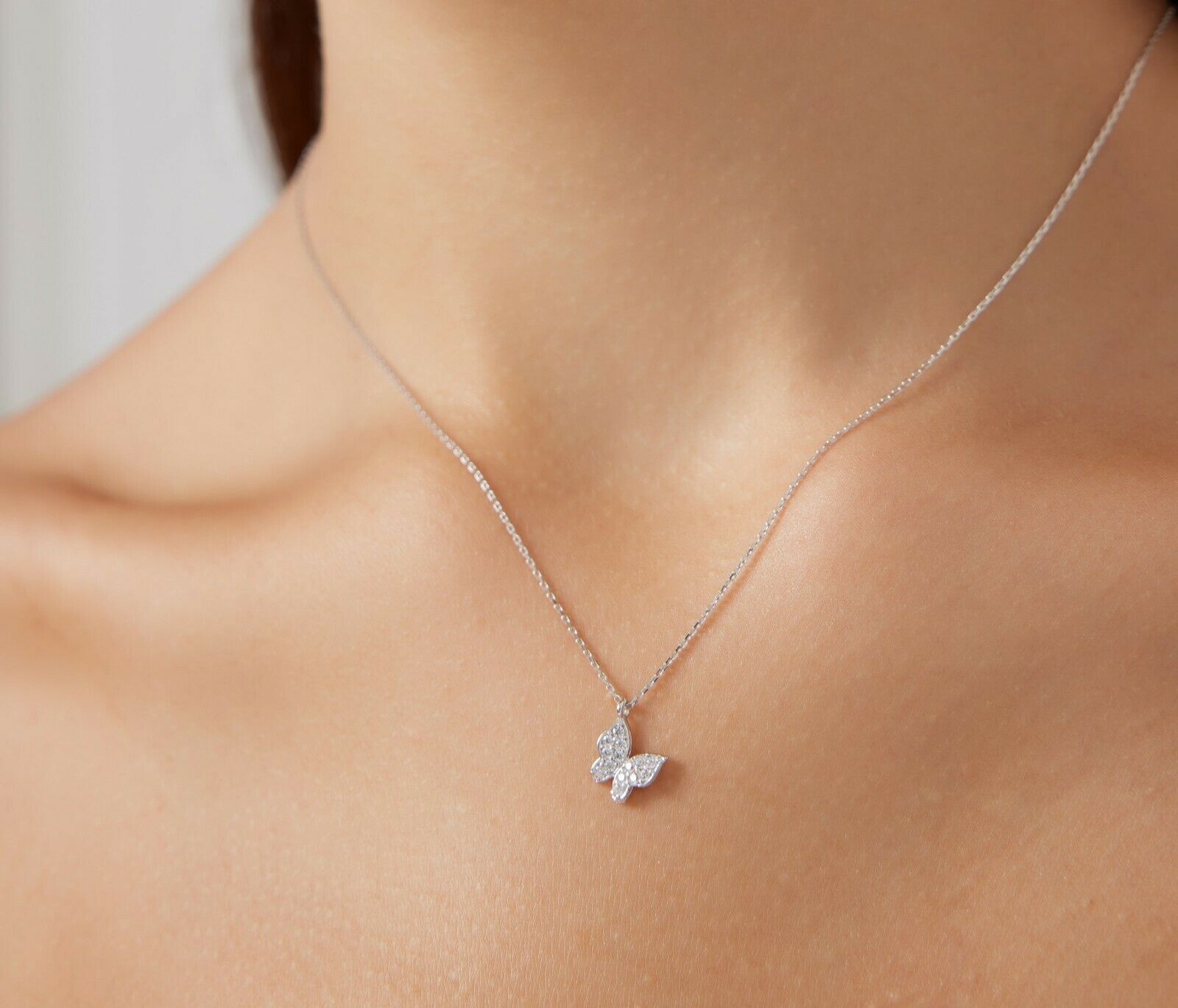 Dainty 14K solid white gold minimalist butterfly necklace with CZ, showcased on a woman's neck.