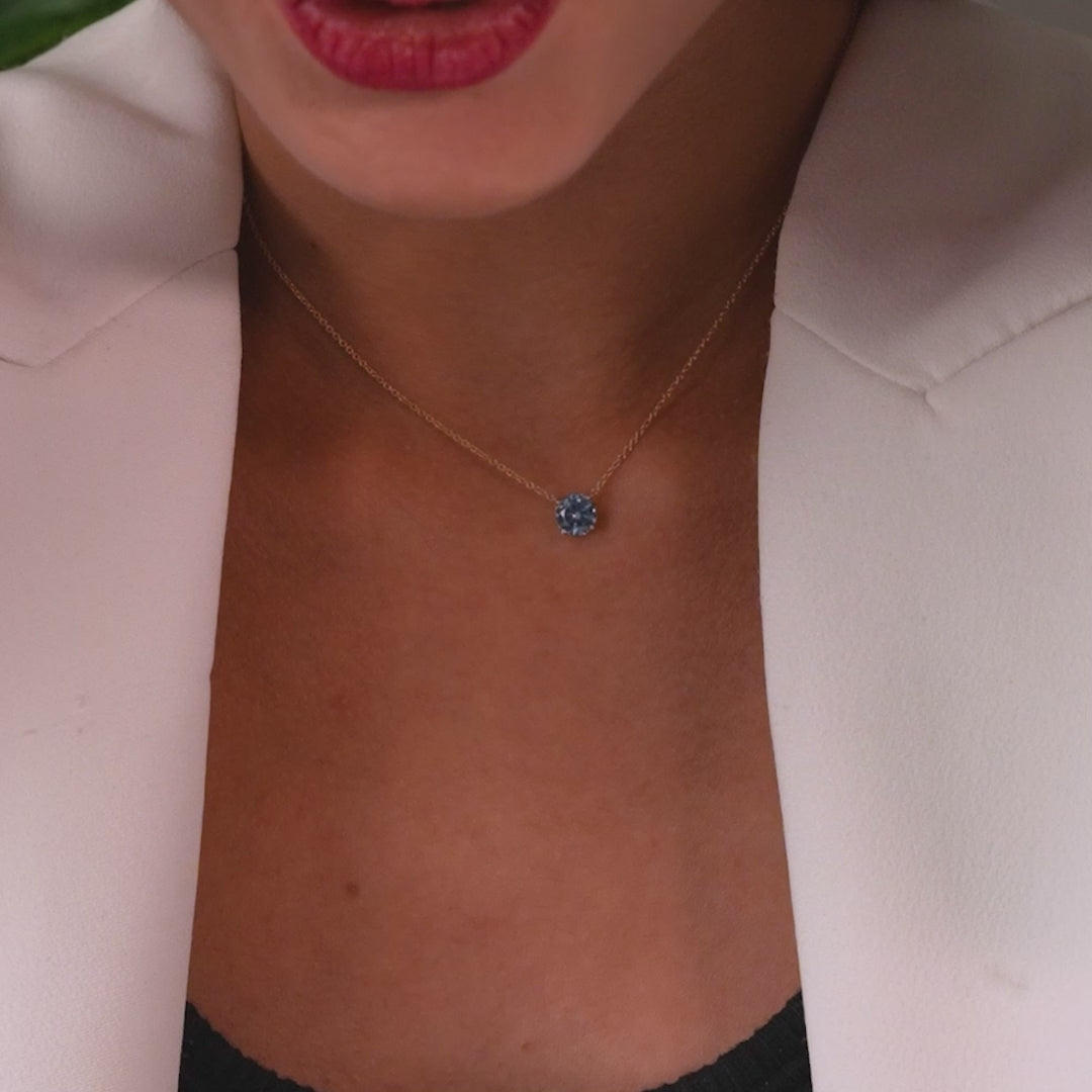 Close-up of a woman's neck adorned with a 14K white gold 6mm prong setting aquamarine solitaire necklace.