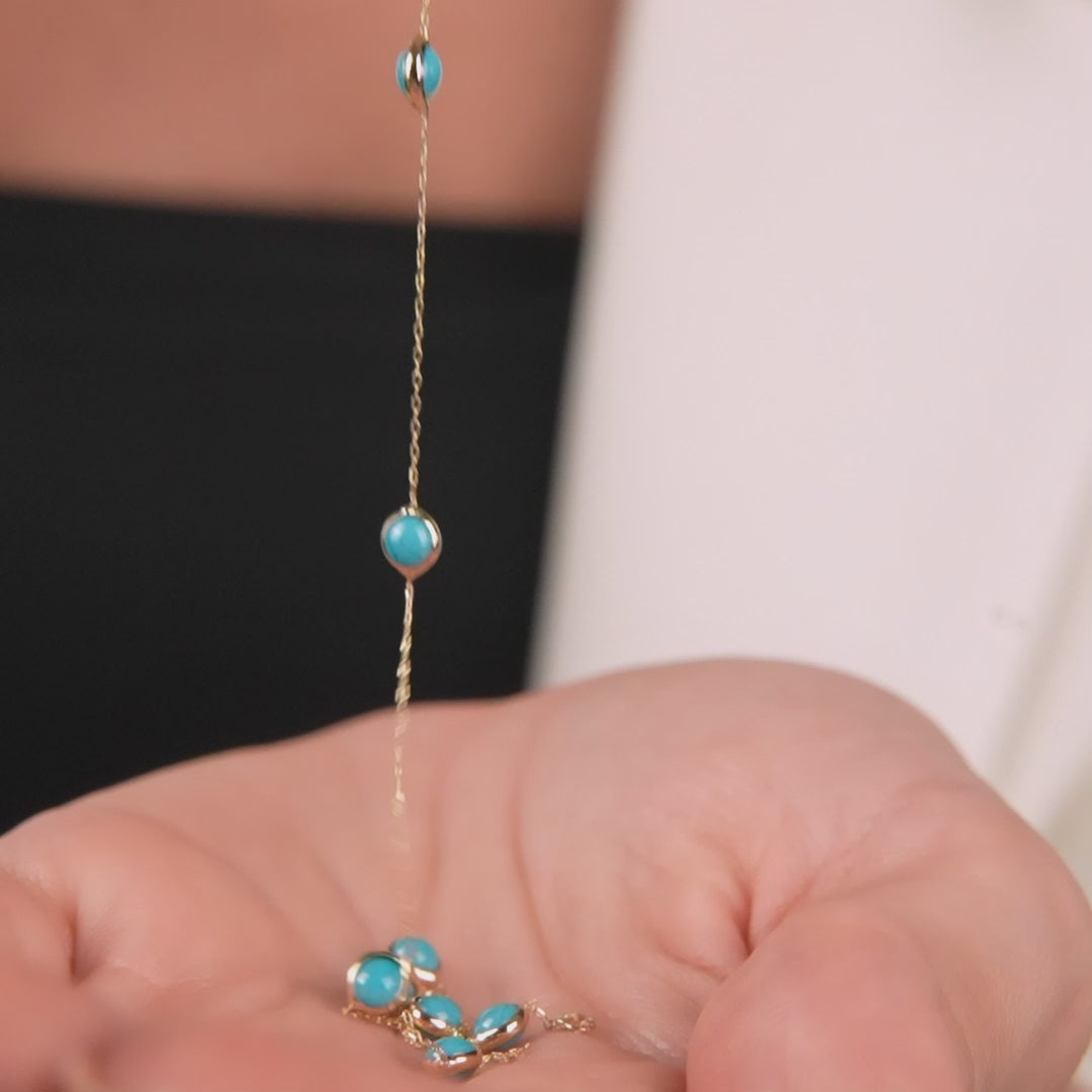 14K solid yellow gold turquoise necklace with beaded station design held in hand, showcasing its elegance and style.