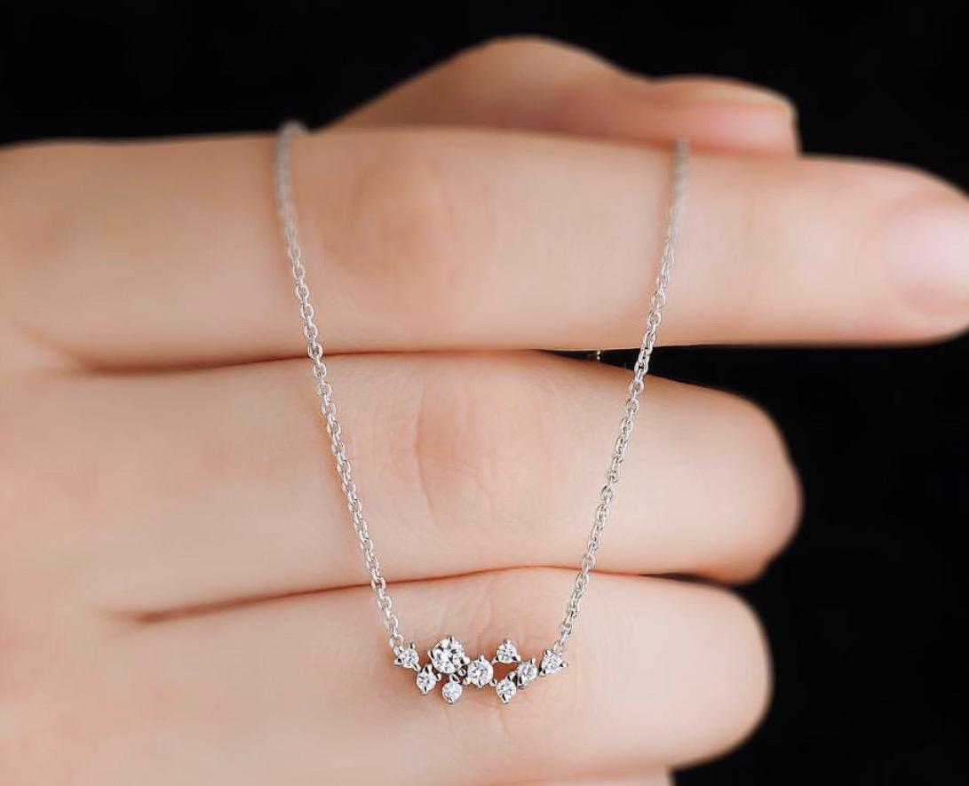 Dainty 14K gold diamond cluster necklace displayed on a hand, featuring sparkling diamonds in a delicate design.