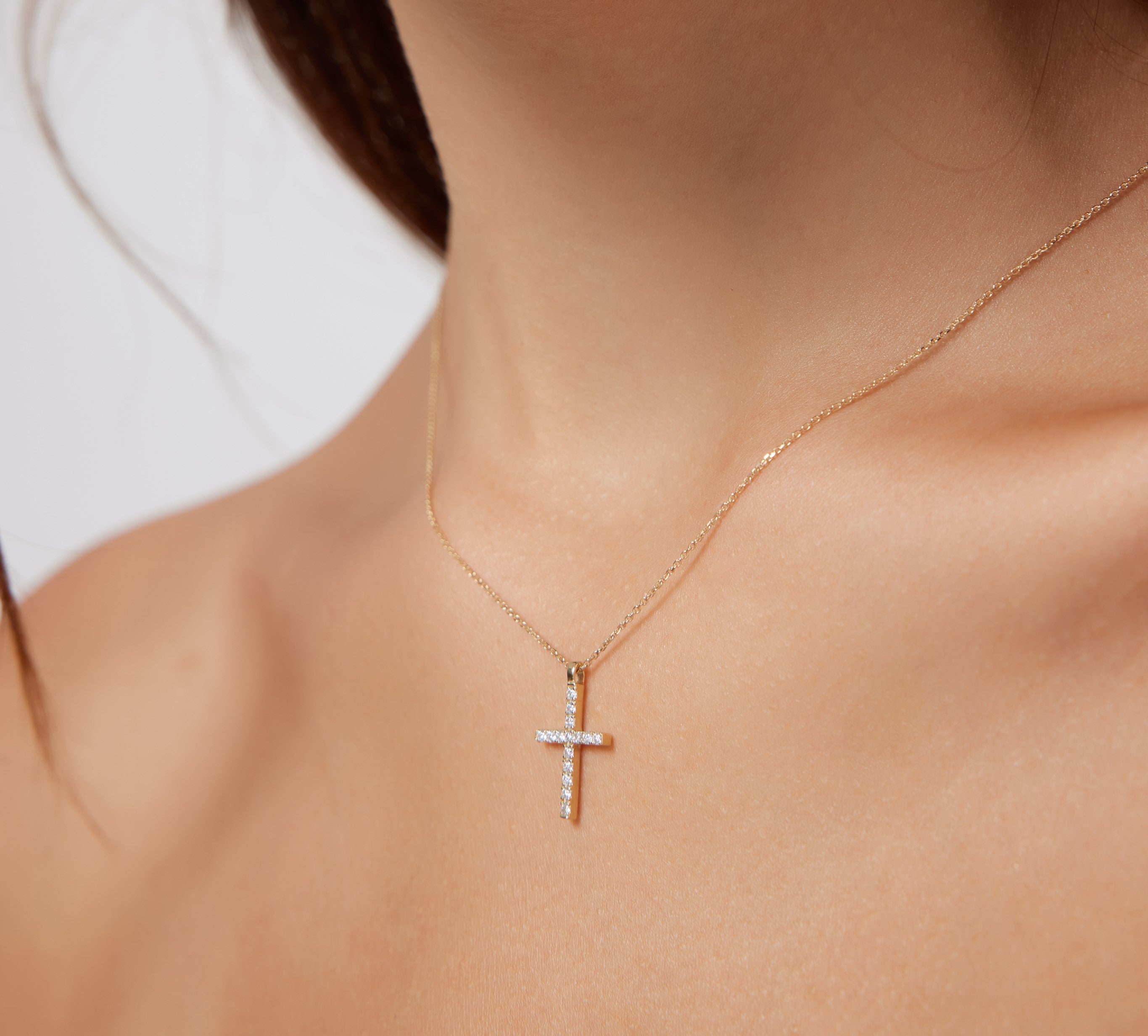 14K solid yellow gold diamond cross necklace worn on a delicate chain, featuring sparkling white diamonds.