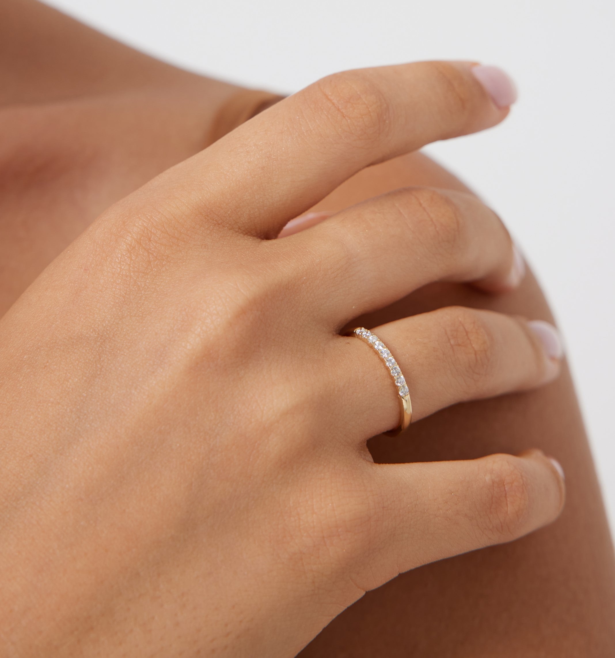 14K yellow gold diamond wedding band featured on a hand, showcasing nine round diamonds with a shiny finish.