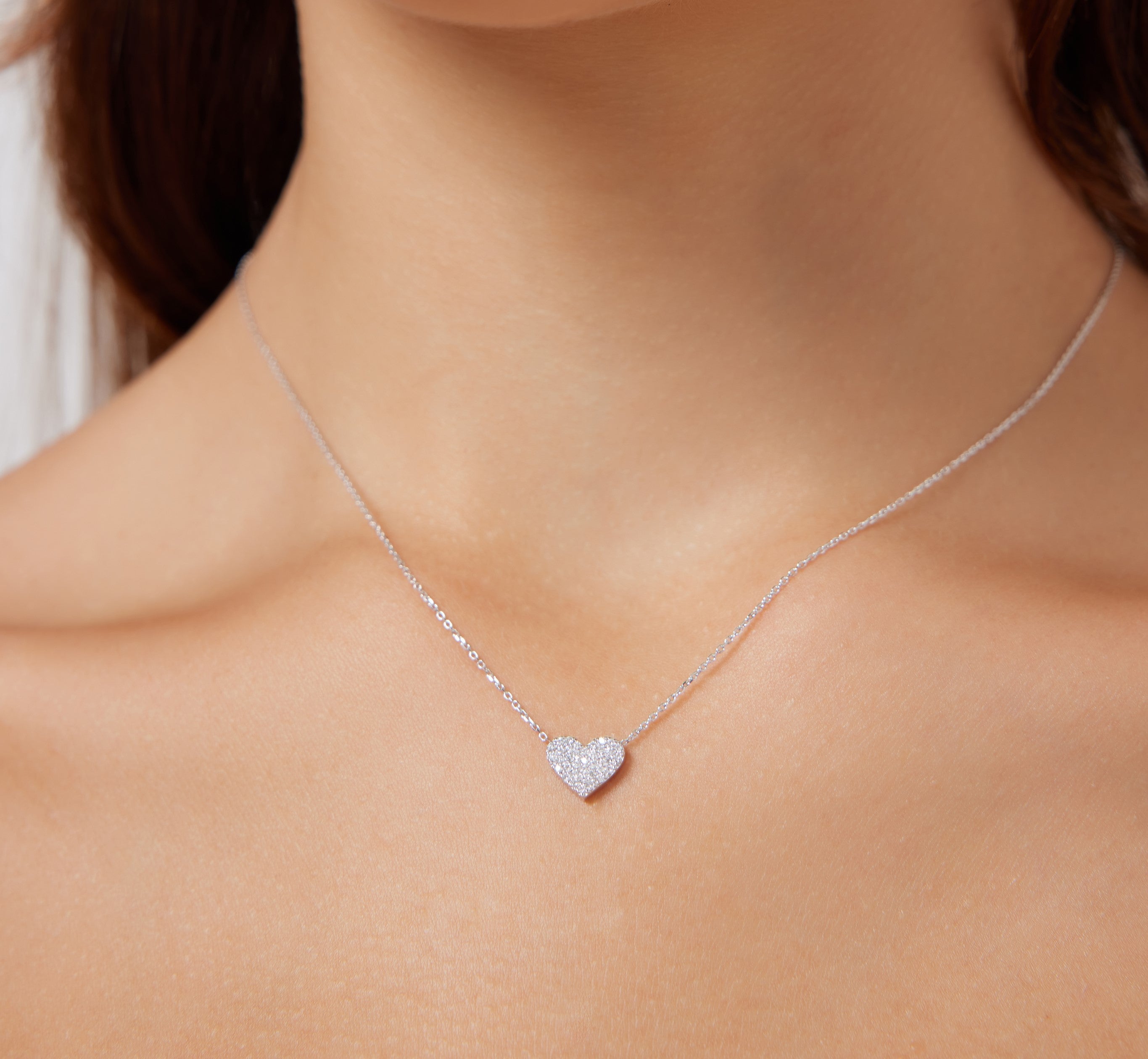 14K solid white gold heart necklace with sparkling diamonds, elegant and minimalist design showcased on a model.