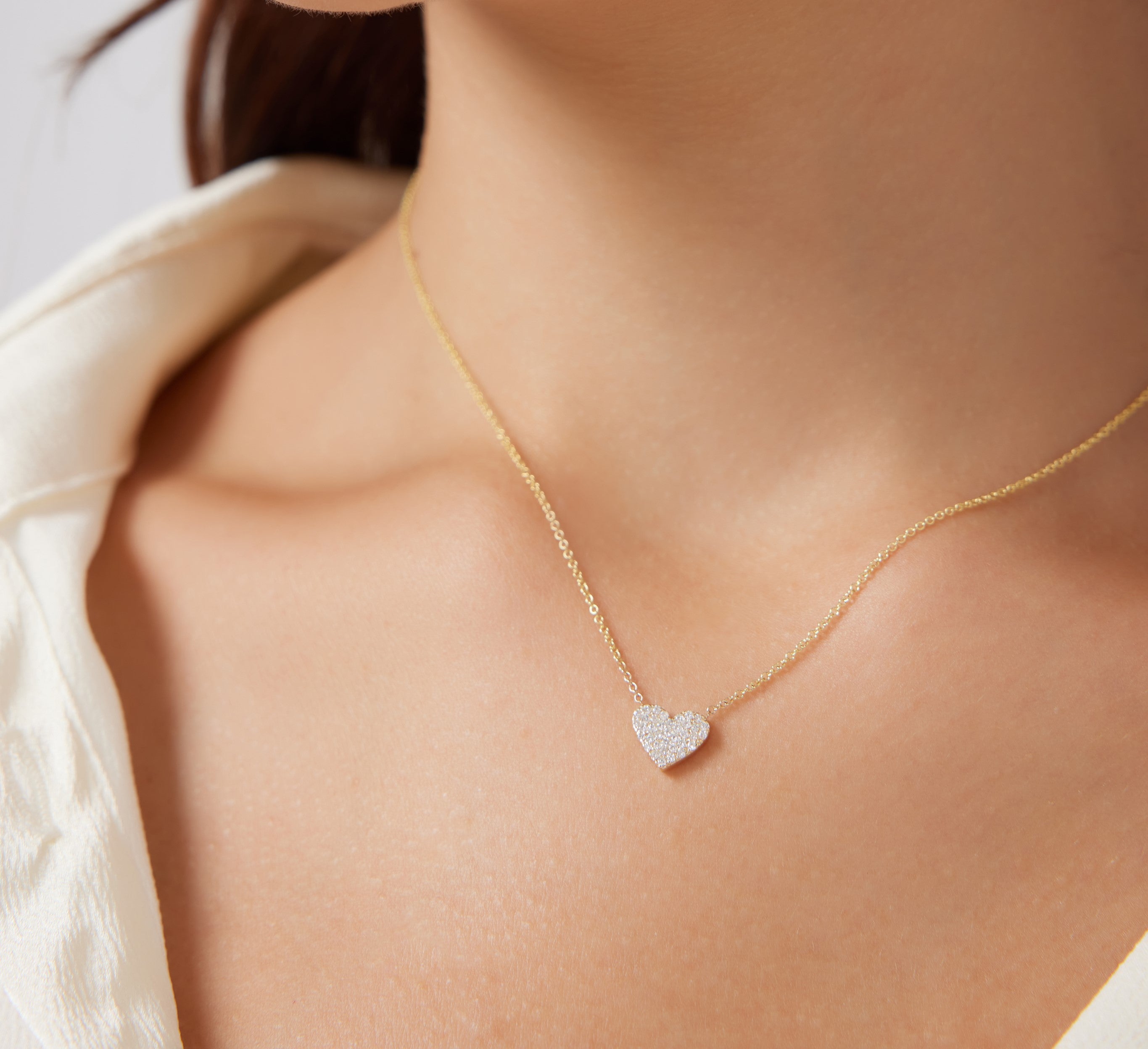 Dainty 14K solid yellow gold heart necklace with sparkling diamonds, shown worn on a model's neck.