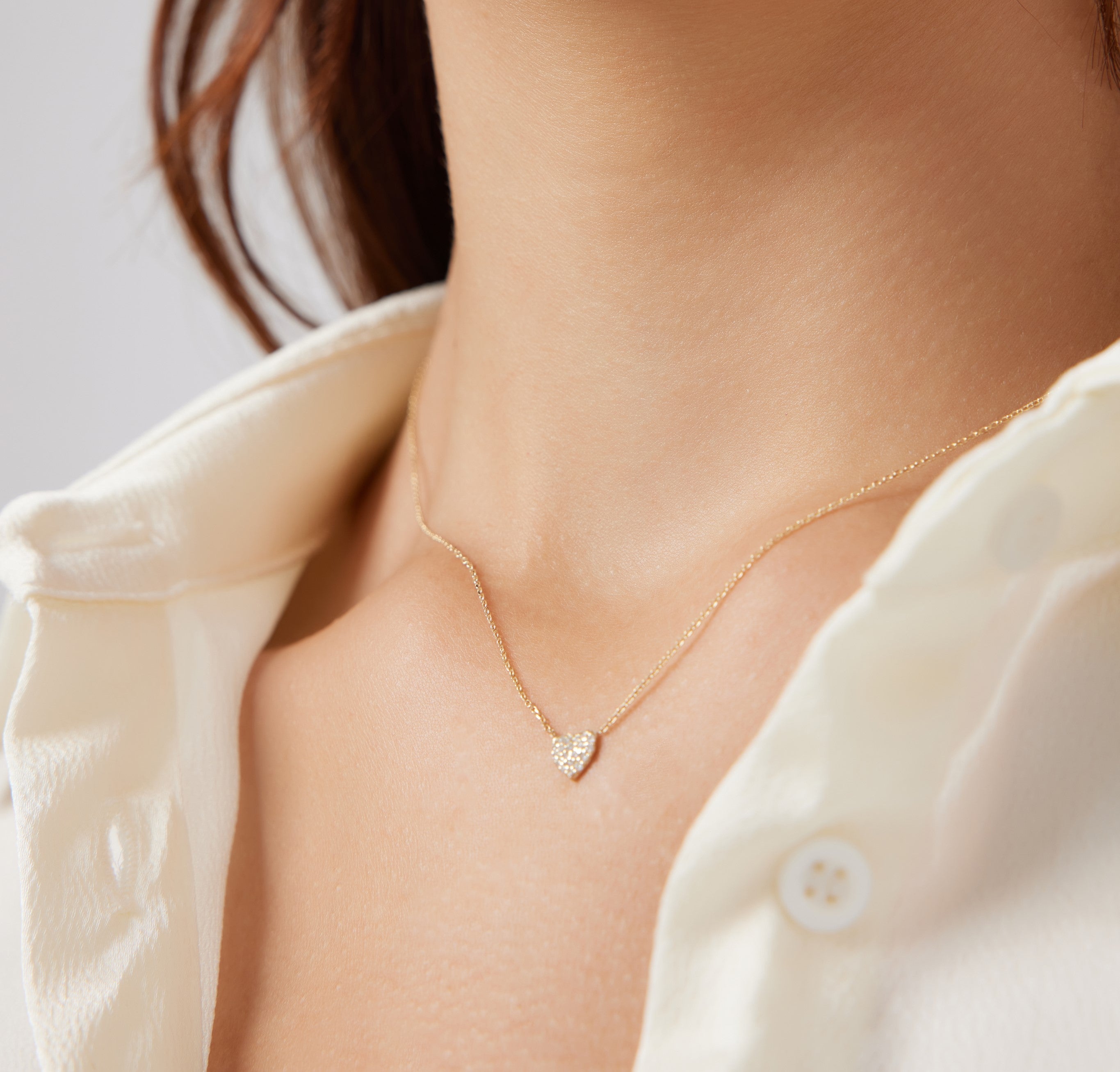 Minimalist 14K solid yellow gold heart necklace with diamonds worn on a woman's neck, featuring a dainty design.