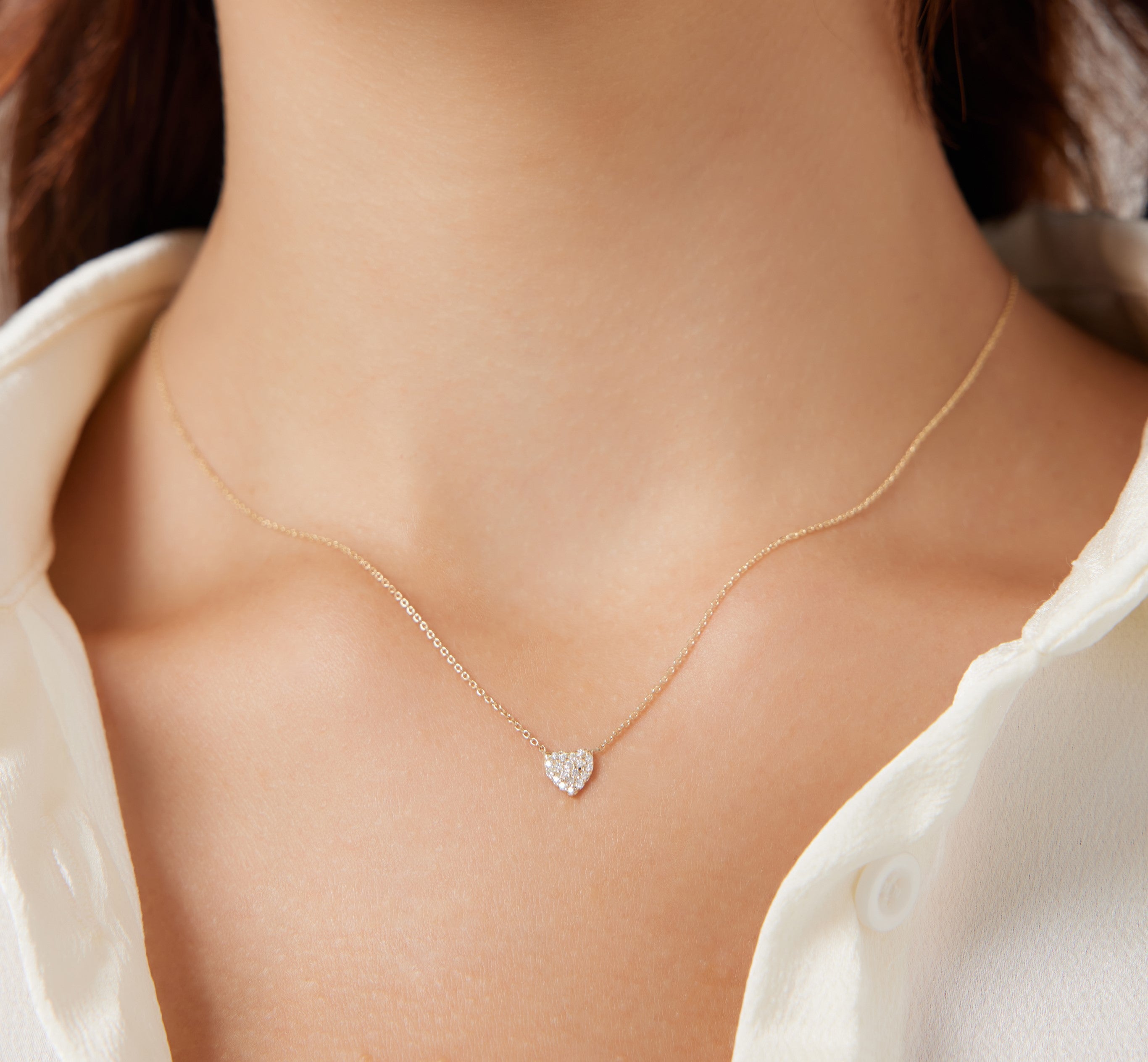 14K solid yellow gold minimalist diamond heart necklace worn on a woman's neck, showcasing its dainty design and sparkle.