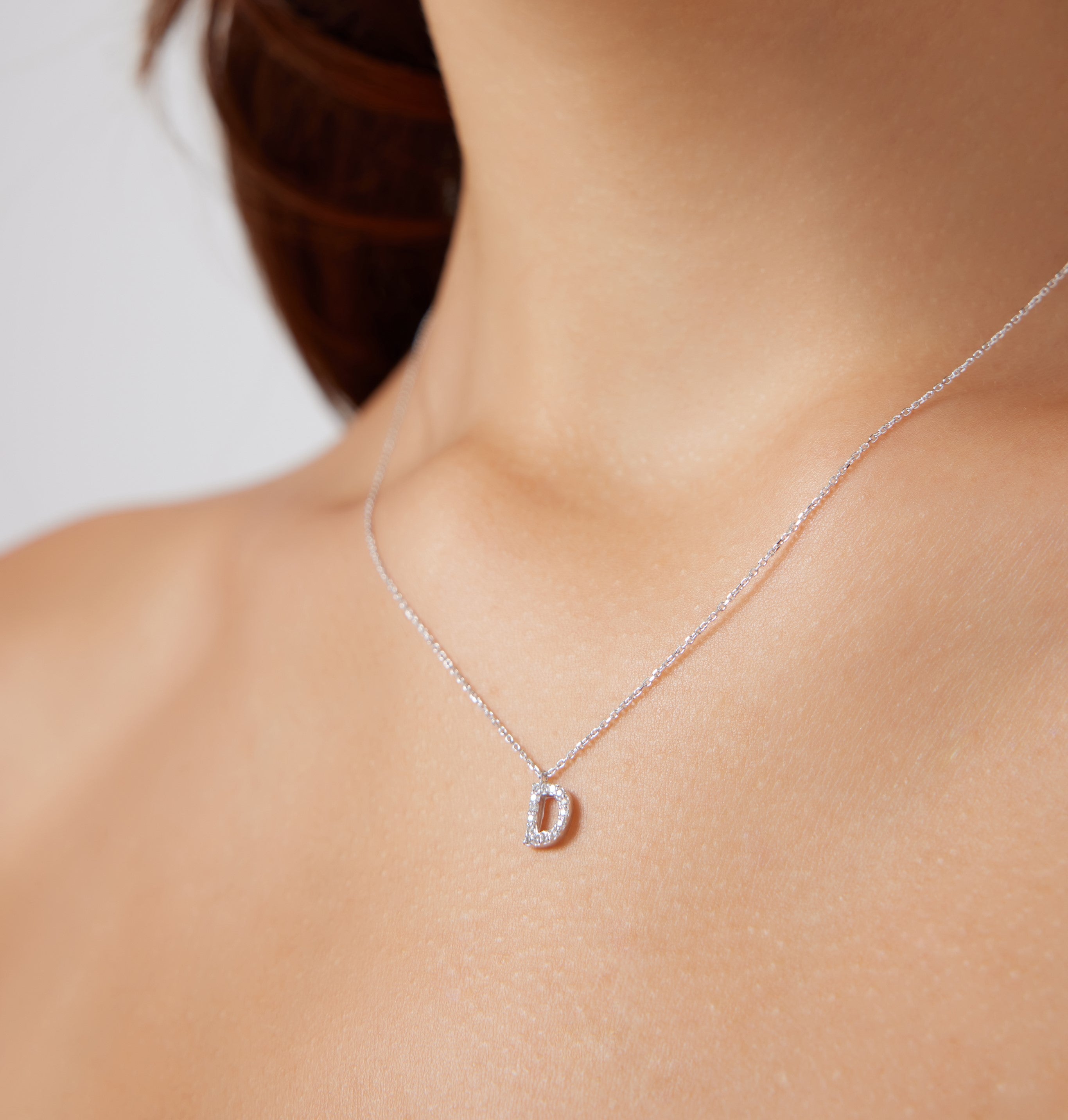 14K white gold initial necklace featuring a diamond-studded letter D, worn elegantly on a model's neck.