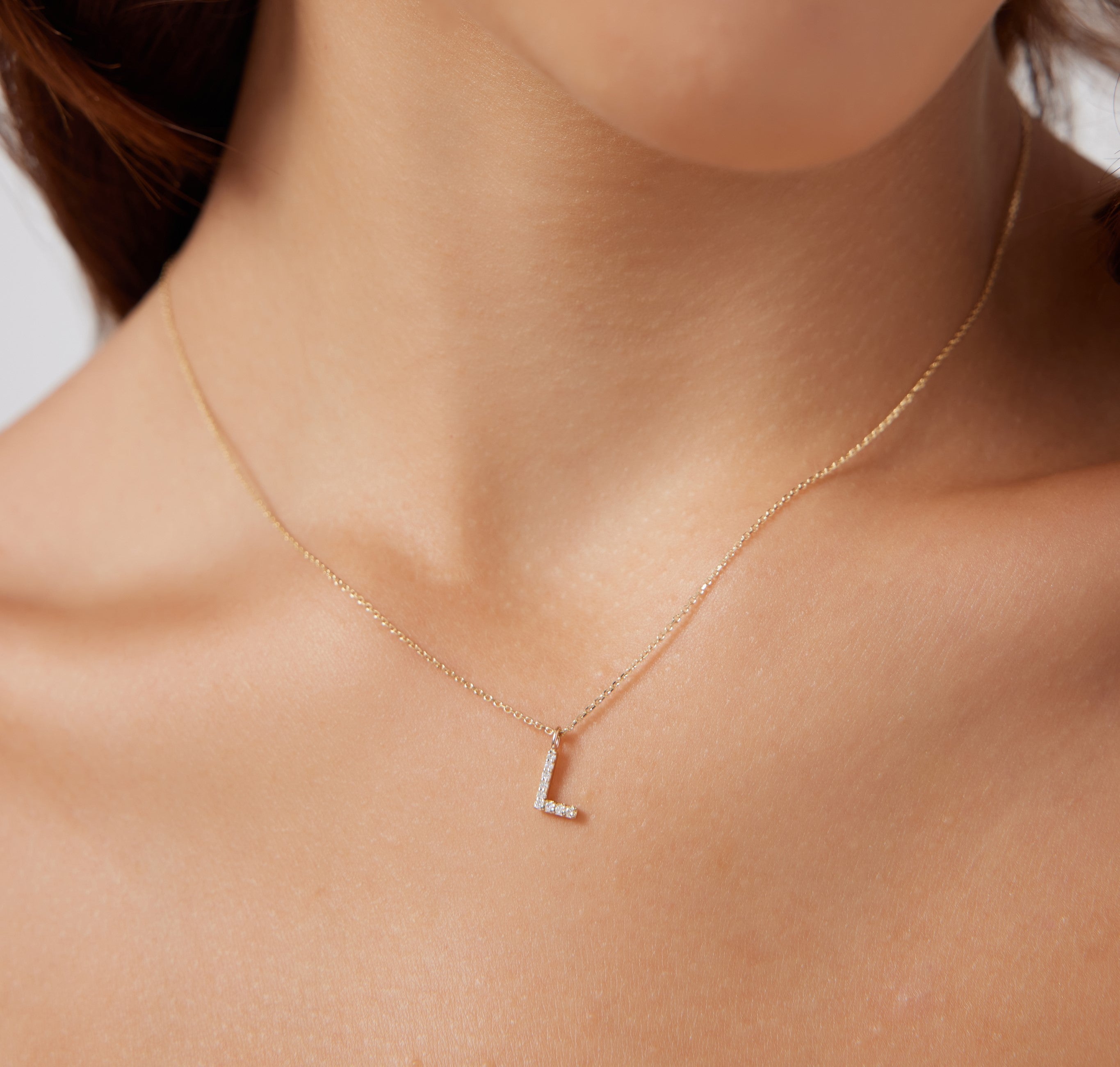 14K yellow gold diamond initial necklace featuring the letter L, adorned with nine sparkling diamonds.