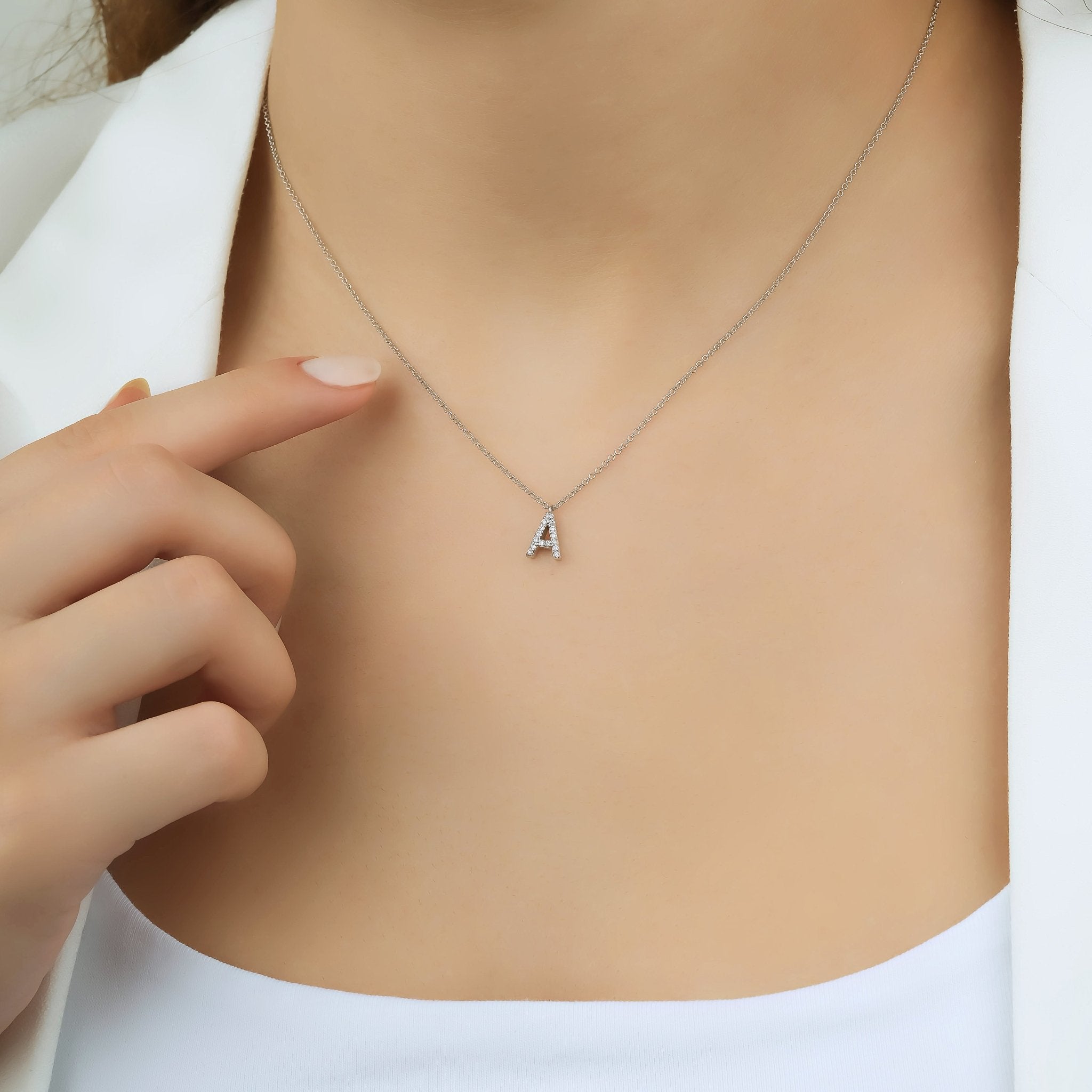 Dainty 14K white gold initial necklace with diamonds, featuring letter A, showcased on a model's neck.