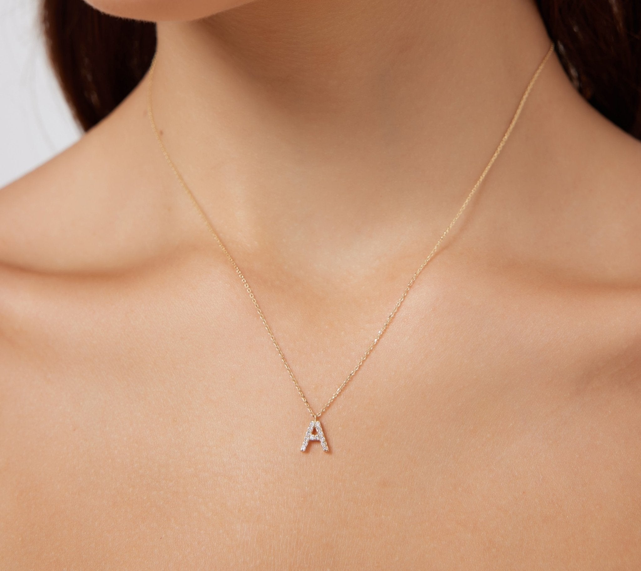 Diamond initial necklace in 14K white gold featuring letter A, showcased on a model's neck.