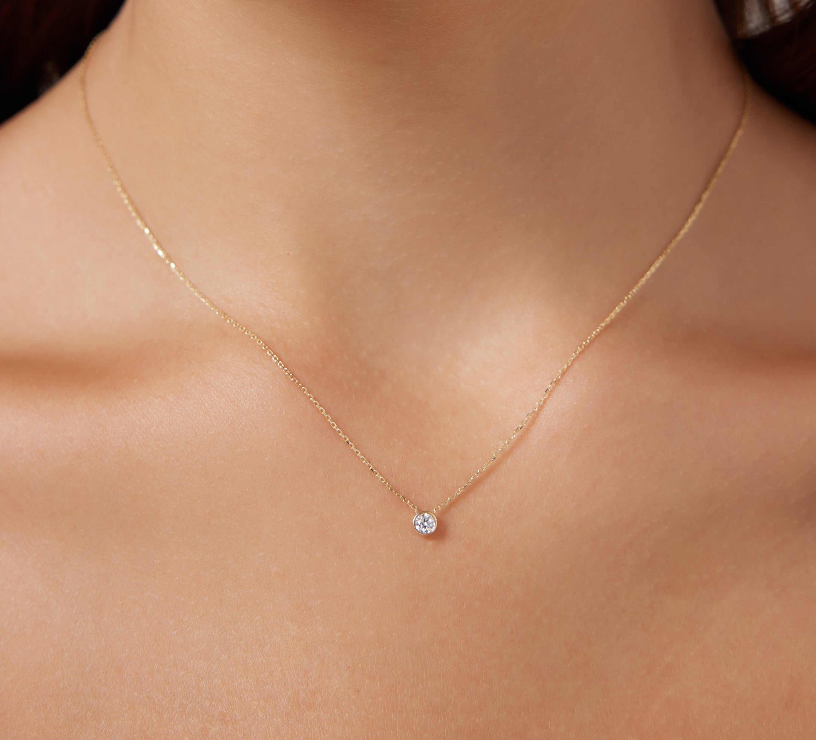 14K solid yellow gold minimalist necklace with 0.12 carat natural diamond solitaire, worn close-up on a neck.