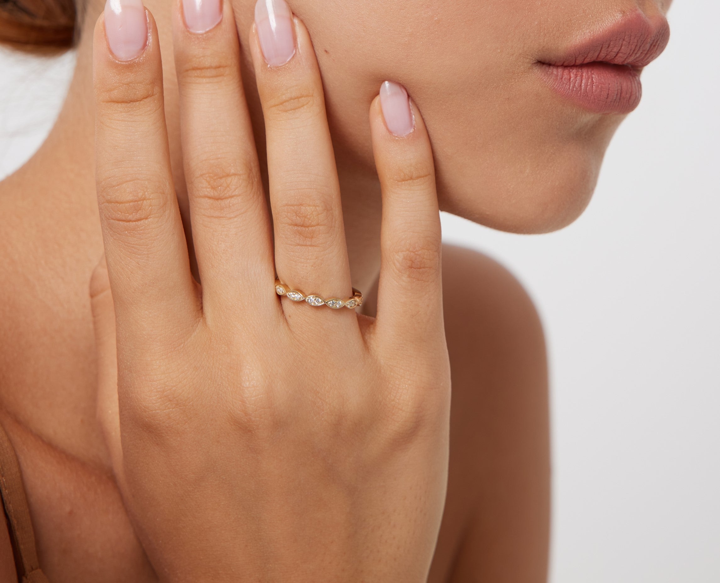Model wearing a 14K yellow gold half eternity diamond wedding band featuring round diamonds on hand.