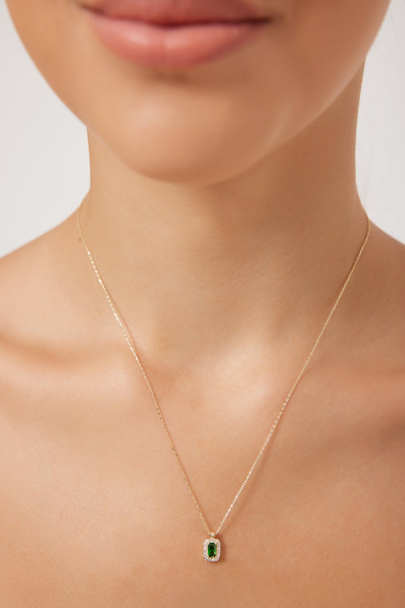 Model wearing a 14K yellow gold emerald cut solitaire emerald necklace, showcasing its elegance and simplicity.