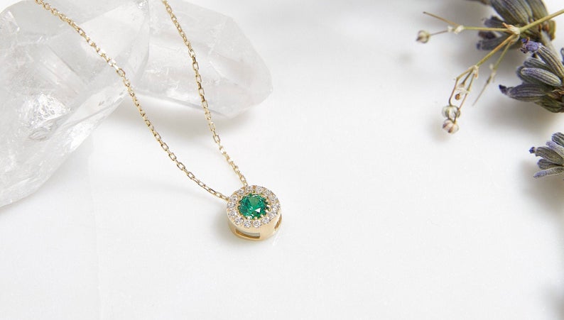 Dainty 14K solid yellow gold round solitaire emerald necklace with CZ on a neutral background.