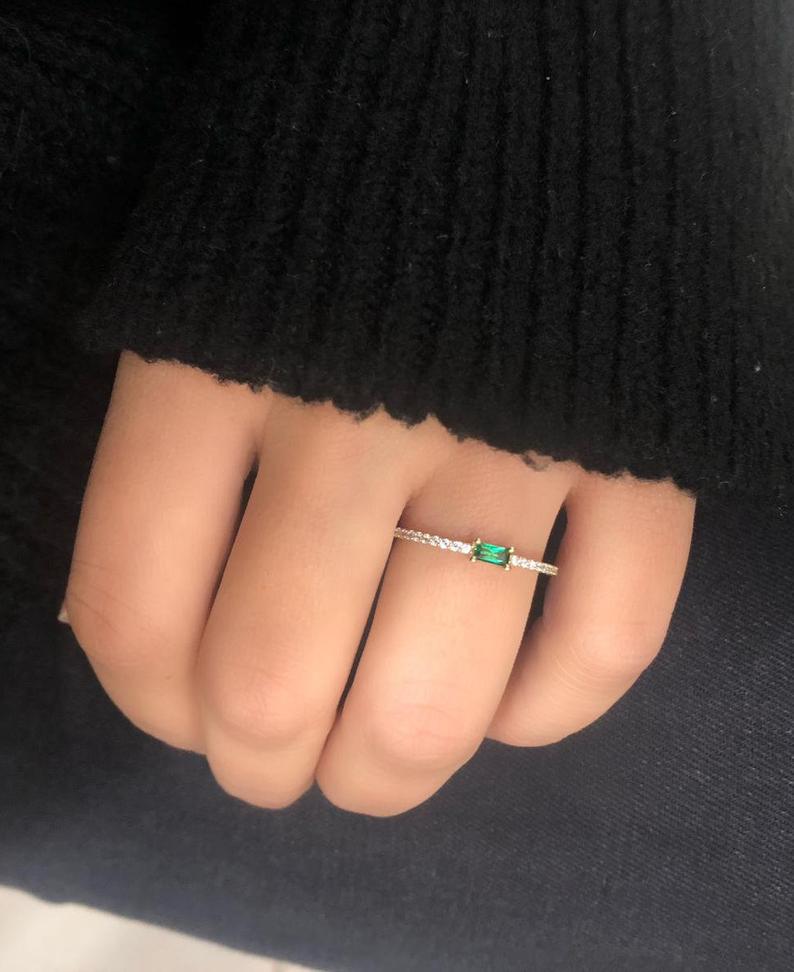 14K yellow gold minimalist emerald wedding ring displayed on a hand, featuring a lab-created emerald and diamond CZ accents.