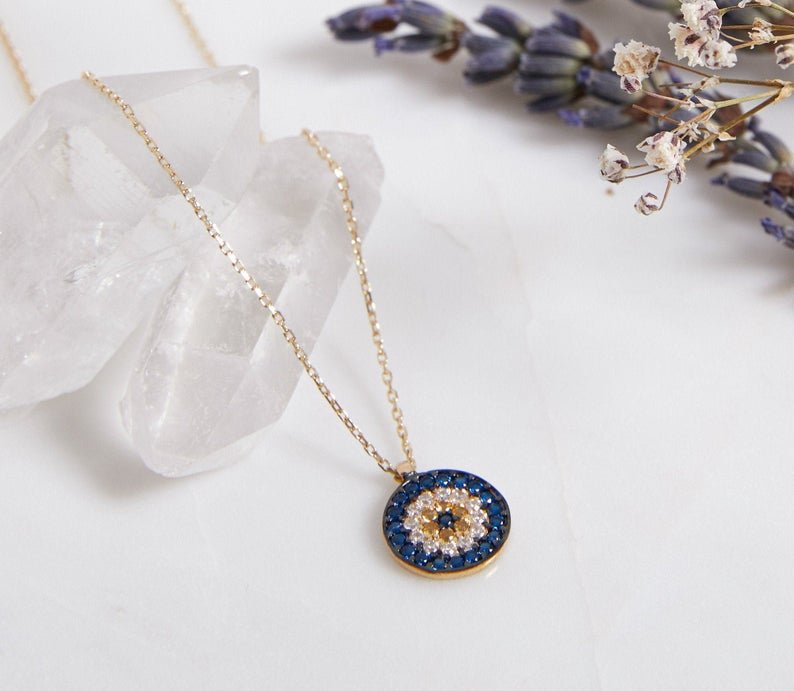 14K solid yellow gold minimalist evil eye necklace with CZ on a crystal background, perfect for everyday wear.