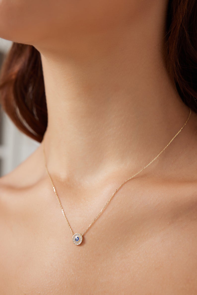 Dainty 14K solid yellow gold round evil eye necklace worn on model's neck, showcasing minimalist design and CZ detail.