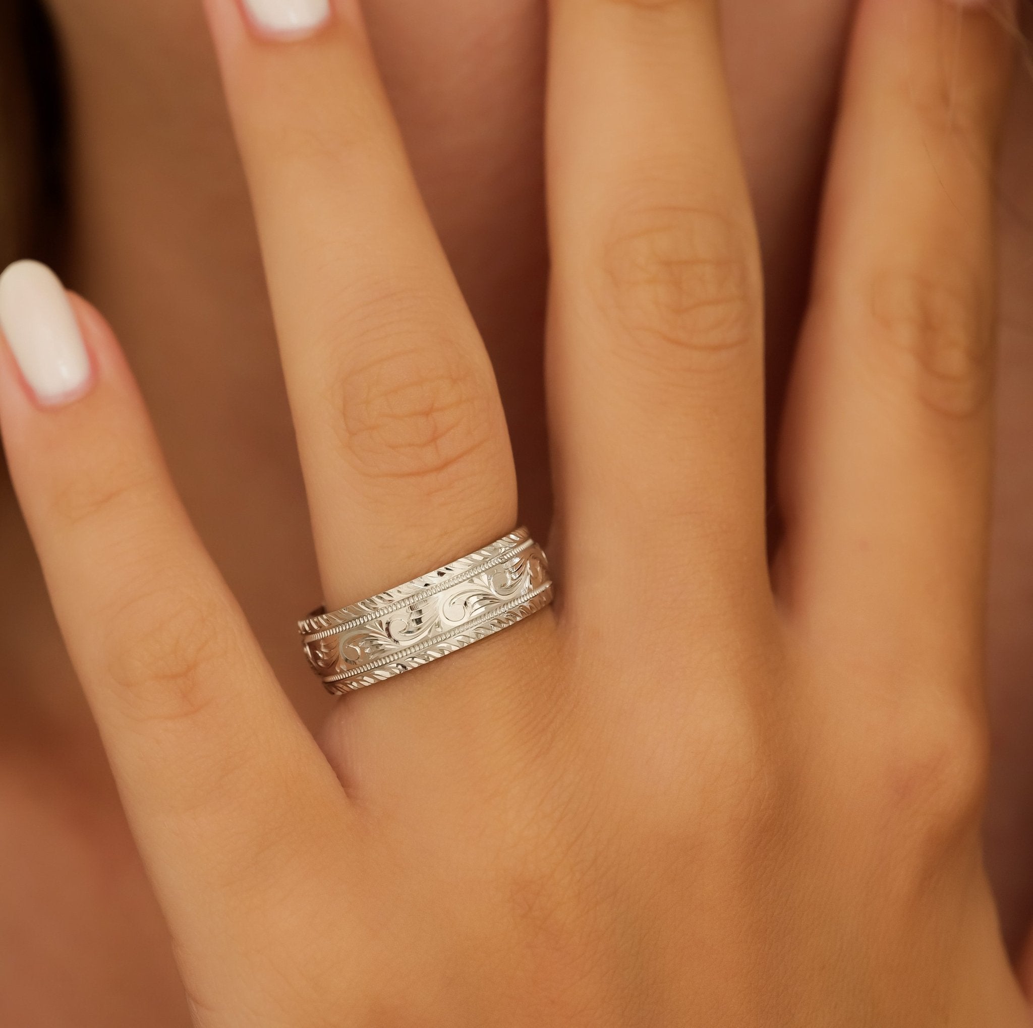 Hand engraved wedding band in solid white gold featuring shiny leaf motifs and milgrain, comfort fitted design.