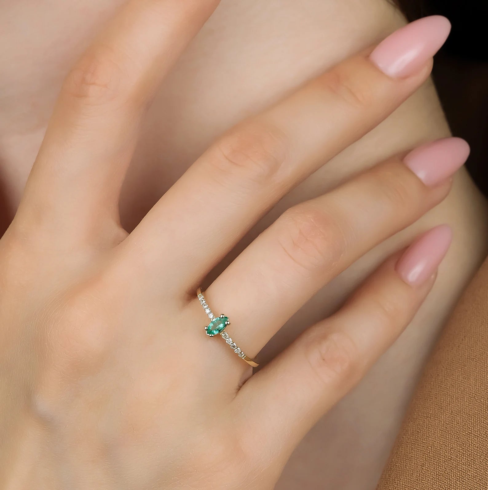 14K gold wedding ring featuring natural marquise emerald and round diamonds on a woman's hand.