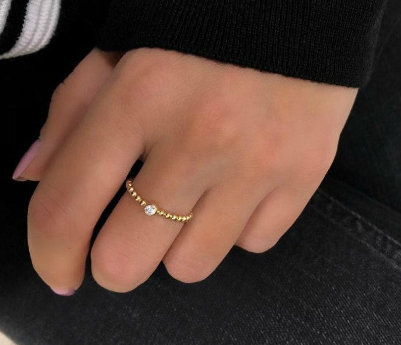 14K yellow gold minimalist solitaire diamond wedding ring worn on hand, showcasing a sparkling 0.10ct diamond.