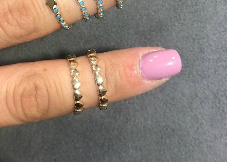 Minimalist 14K solid yellow gold heart rings displayed on a finger with pink nail polish, showcasing delicate design.