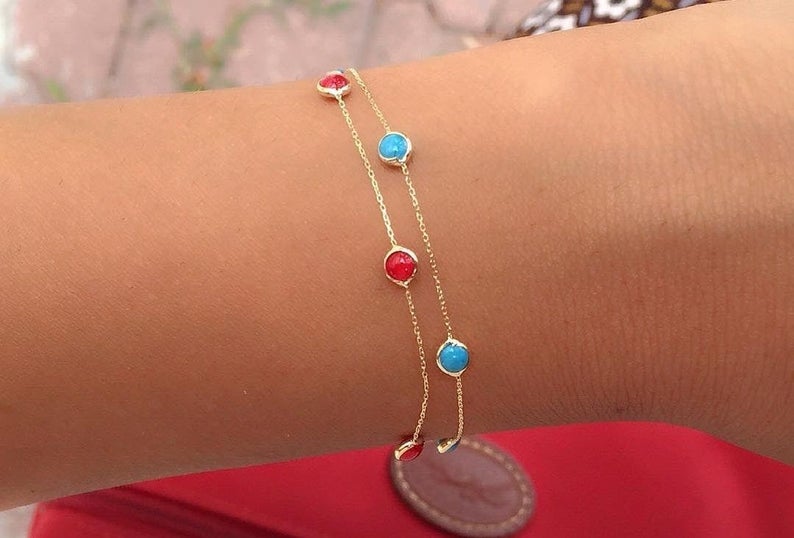 Dainty 14K solid yellow gold beaded bracelet with red and blue gemstones on wrist, perfect for everyday wear.