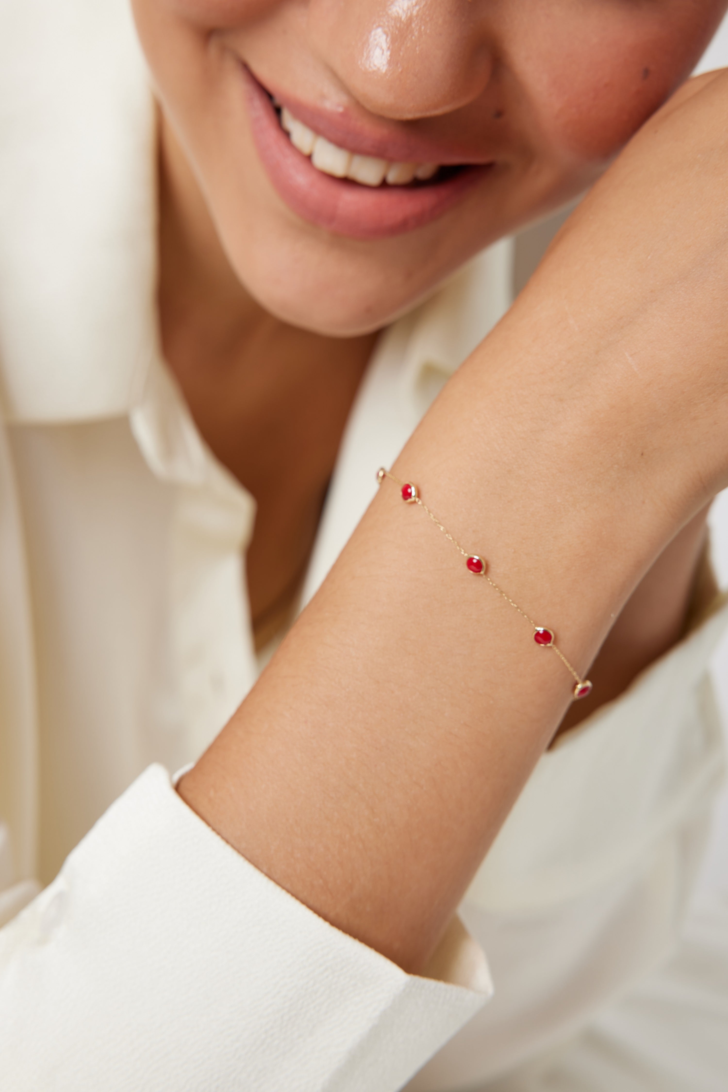 Model wearing a 14K solid yellow gold beaded ruby station bracelet, showcasing its dainty and minimalist design.