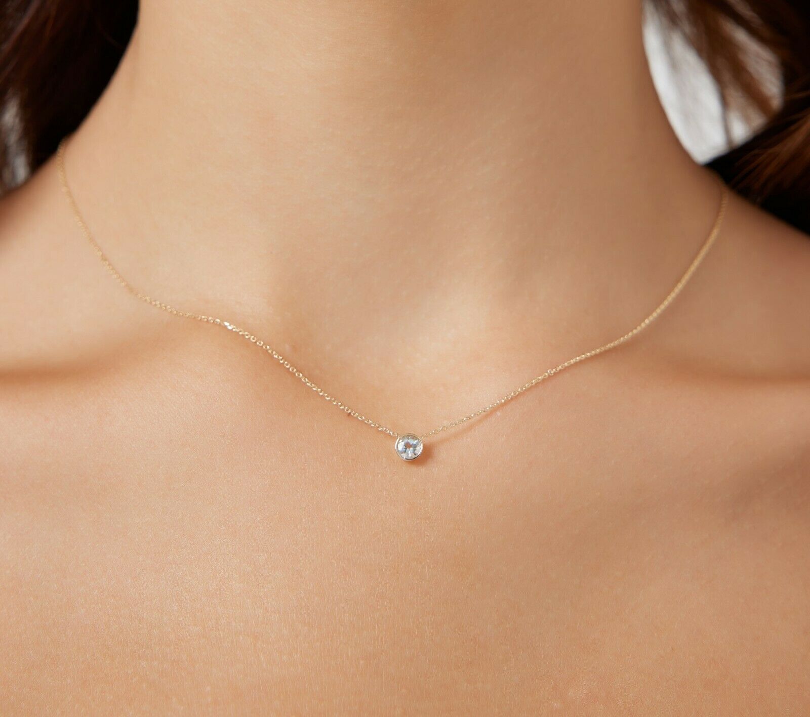 14K yellow gold 6mm bezel set aquamarine solitaire necklace worn on a model's neck, showcasing minimalist elegance.
