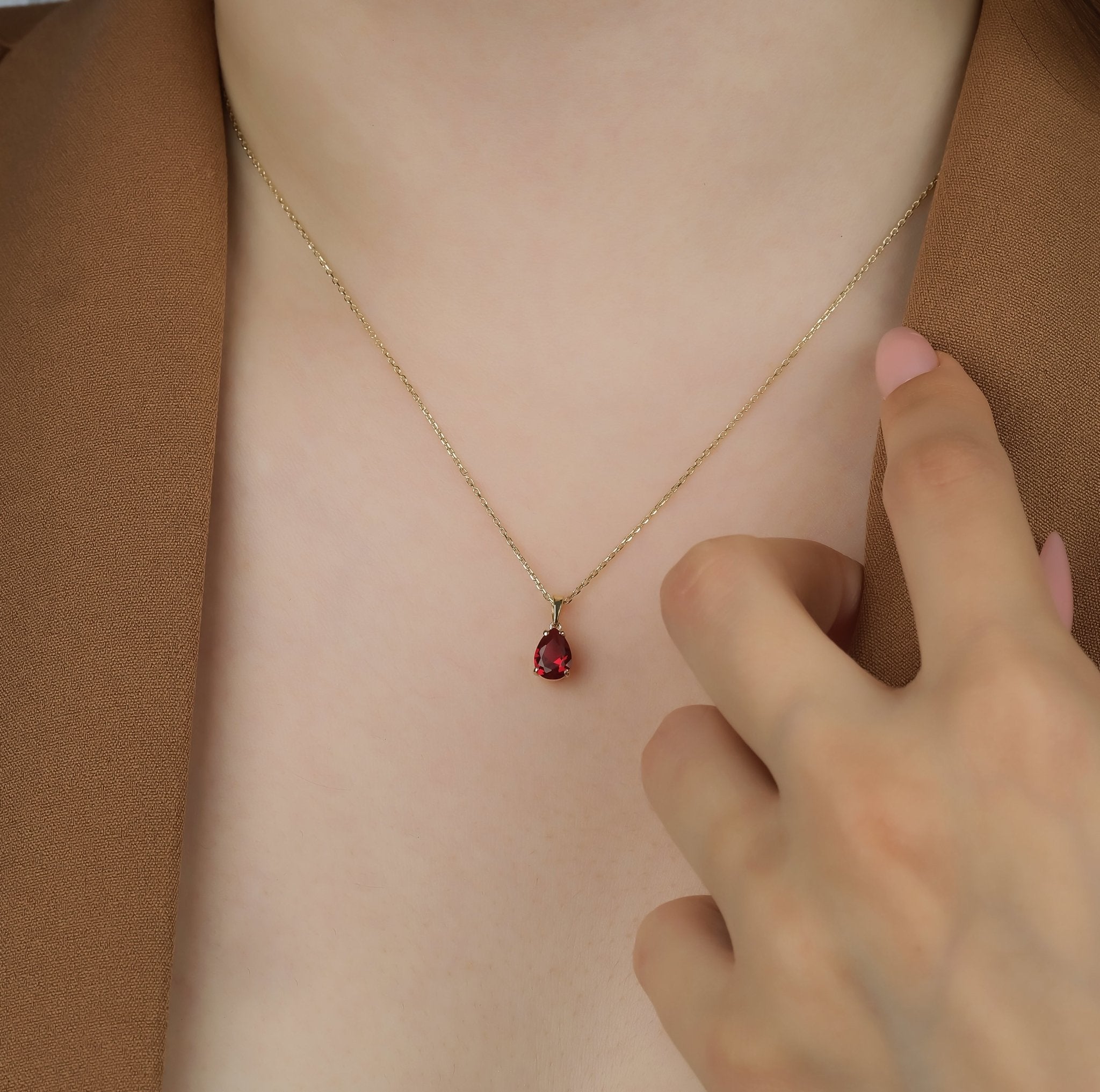 14K gold pear shape ruby solitaire necklace worn on model, highlighting 1 carat ruby pendant with elegant design.