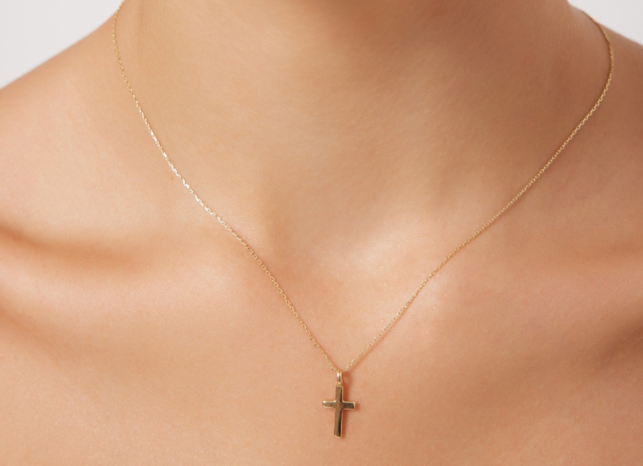 14K solid white gold cross necklace worn by a model, showcasing its dainty minimalist design.