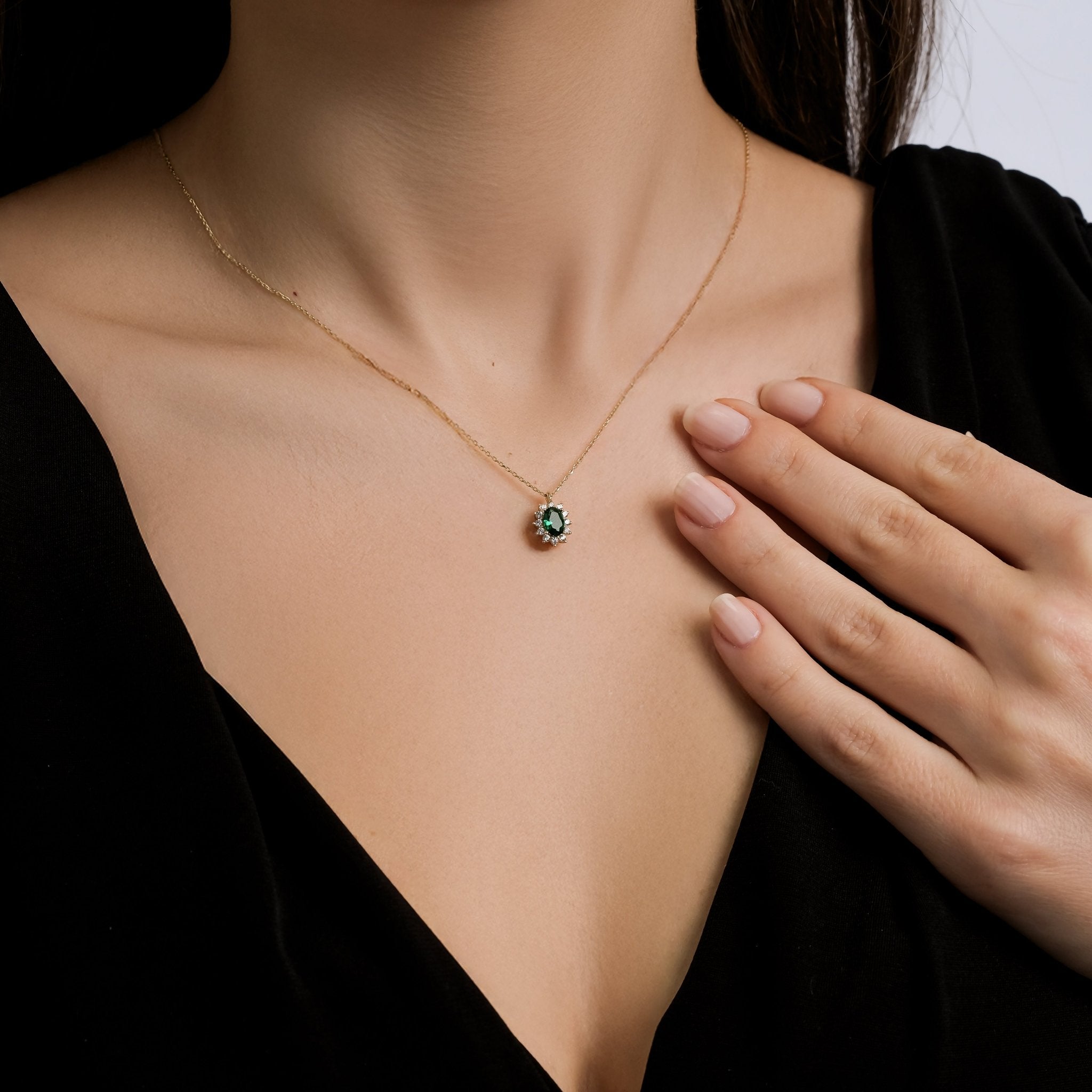 Dainty 14K solid yellow gold oval emerald necklace worn by a woman, showcasing its minimalist elegance.