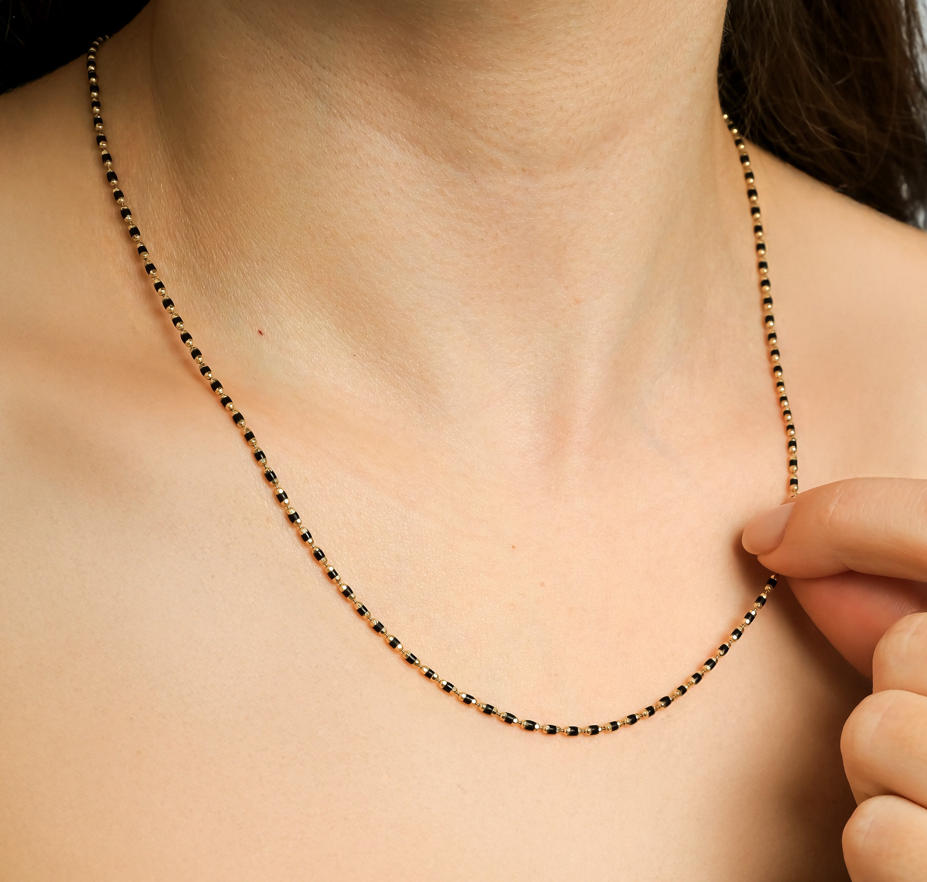 14K solid yellow gold black enamel beaded necklace worn around the neck, showcasing its delicate design and minimalist style.