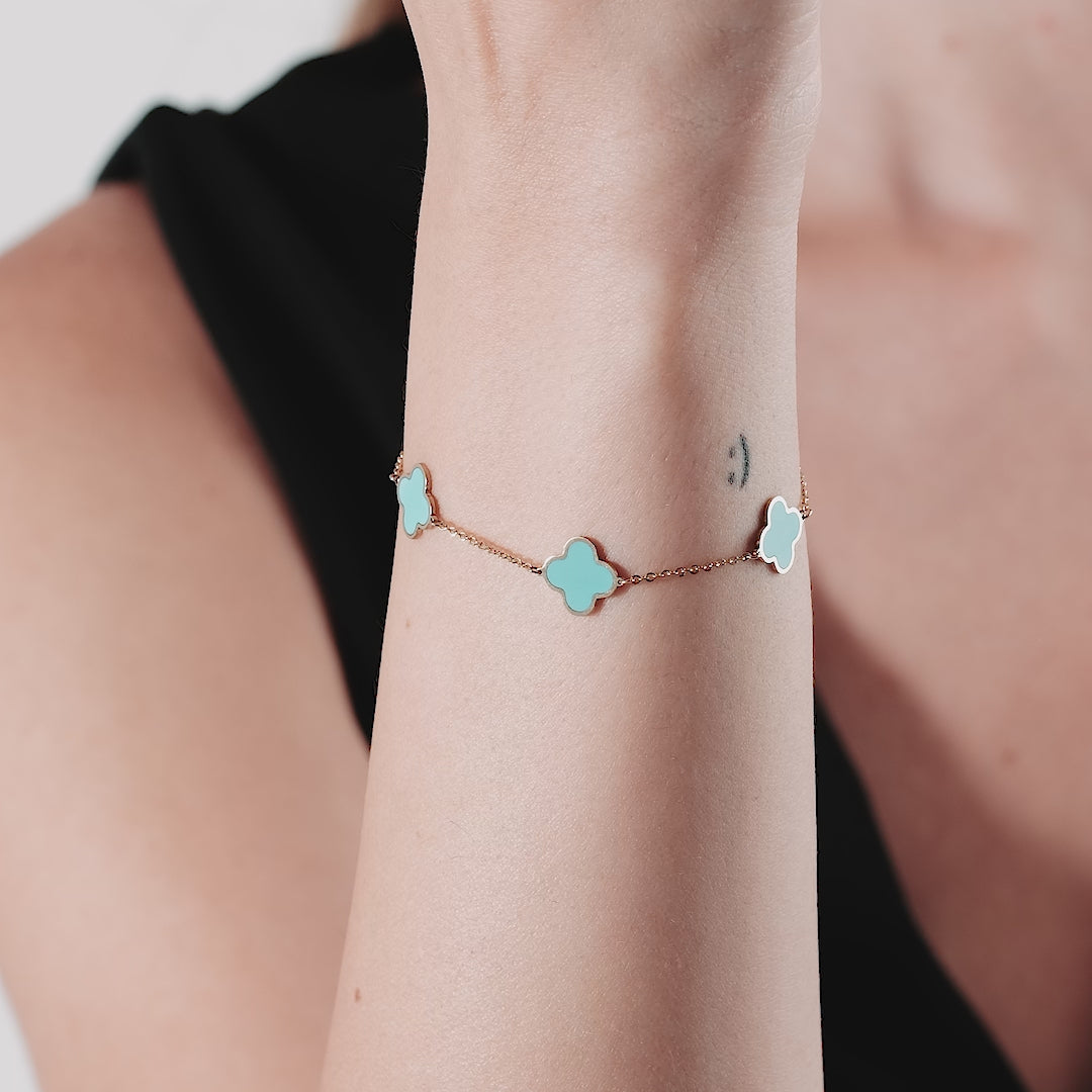 Delicate 14K solid yellow gold station bracelet with turquoise four leaf clovers on a woman's wrist.