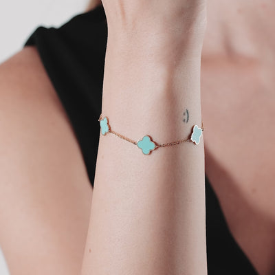 Delicate 14K solid yellow gold station bracelet with turquoise four leaf clovers on a woman's wrist.
