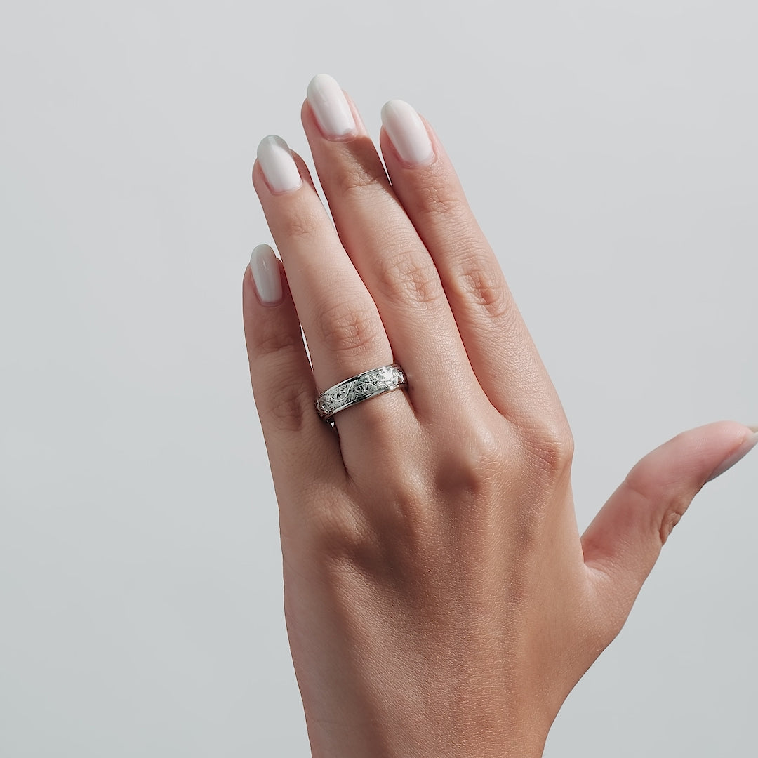 Hand wearing a 6mm 10K White Gold Hand Engraved Wedding Band with shiny leaf motifs.