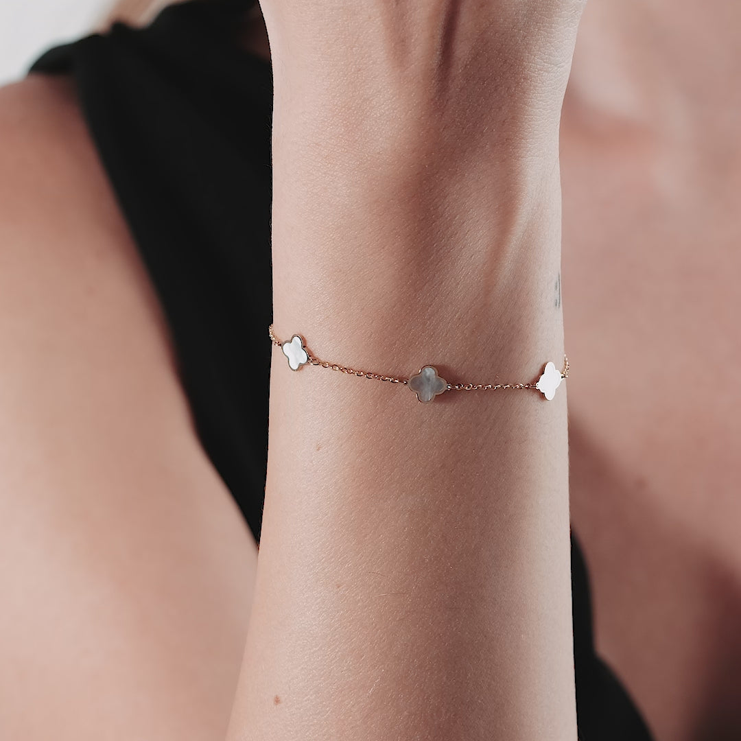 Model wearing a dainty 14K solid yellow gold mother of pearl four leaf clover bracelet on wrist.