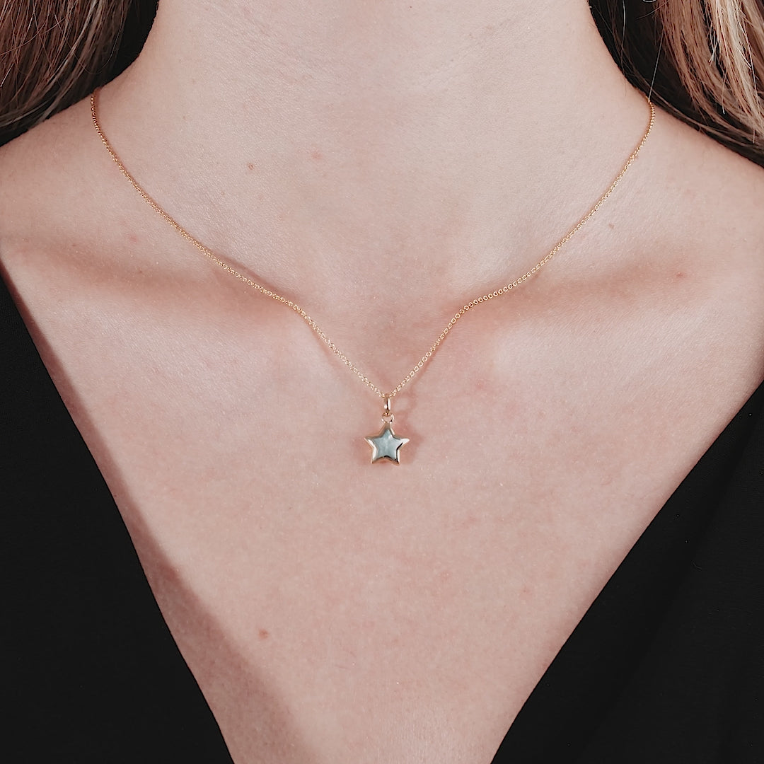 14K yellow gold minimalist necklace featuring a natural mother of pearl puffed star pendant worn elegantly.