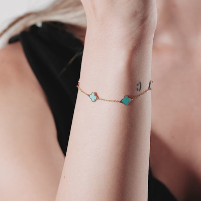 14K yellow gold four leaf clover bracelet with turquoise accents on model's wrist, showcasing a delicate design.