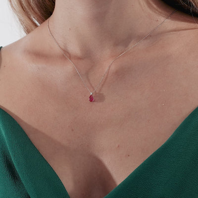 14K yellow gold ruby solitaire necklace worn with a green dress, showcasing the elegant pendant and delicate chain.