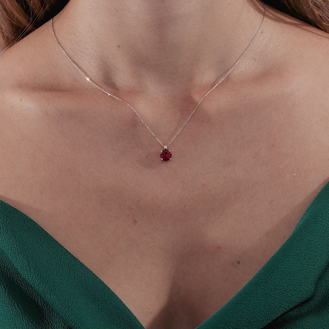 14K solid yellow gold ruby solitaire necklace with natural diamond, elegantly worn with a green dress.