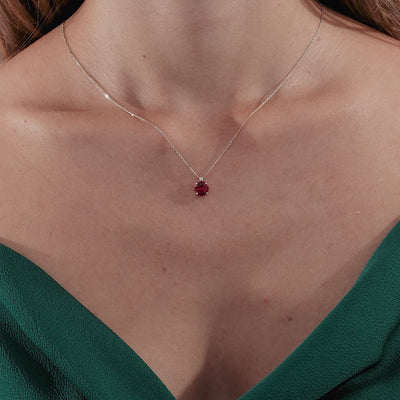 14K solid yellow gold ruby solitaire necklace with natural diamond, elegantly worn with a green dress.