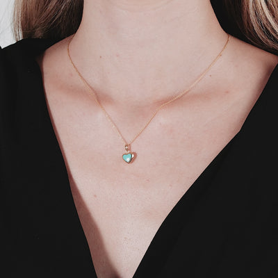 14K yellow gold minimalist necklace featuring a turquoise puffed heart pendant worn by a model.