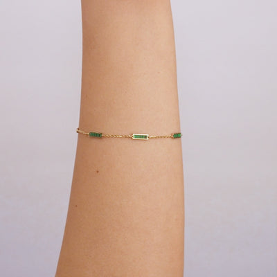 14K solid yellow gold malachite bar bracelet worn on a wrist, featuring green malachite stones and lobster claw clasp.
