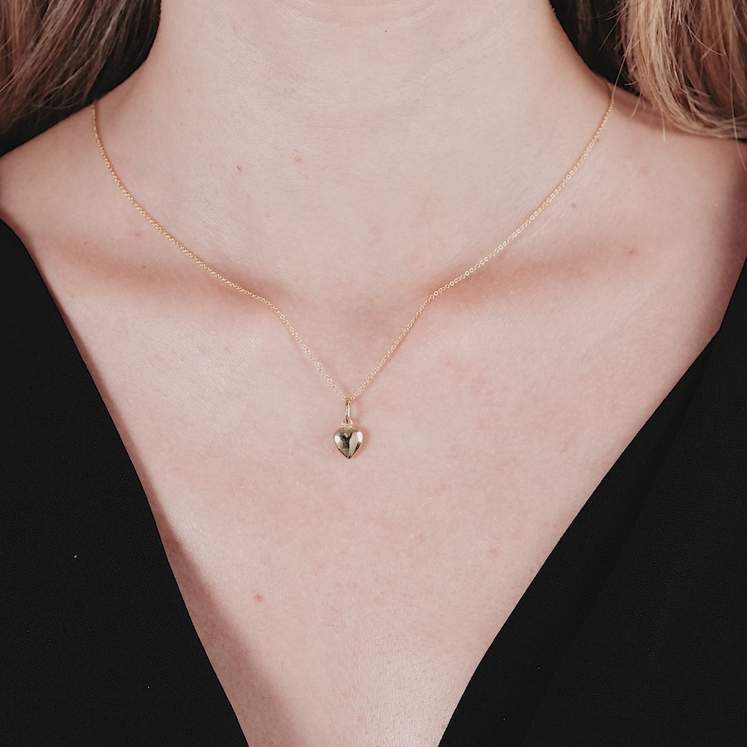 Model wearing a 14K yellow gold dainty puff heart pendant necklace, showcasing its elegant and minimalist design.
