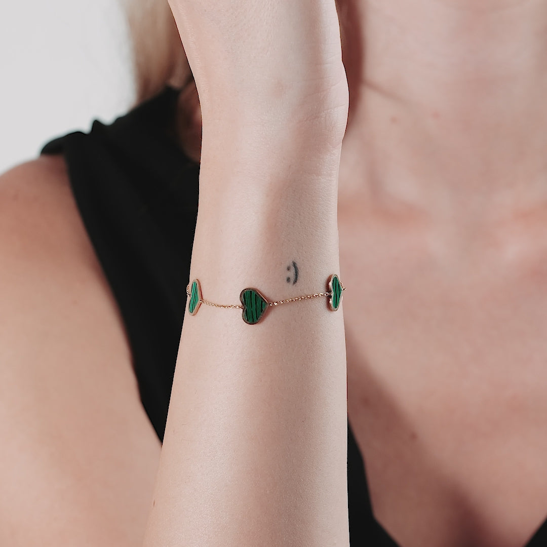 14K solid yellow gold station malachite heart bracelet worn on wrist, showcasing vibrant green hearts and elegant design.