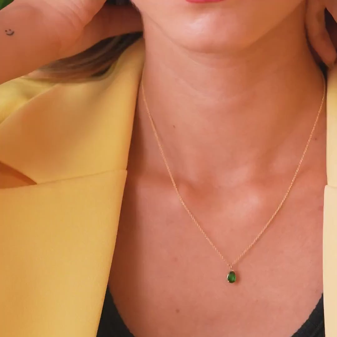 Model wearing a 14K yellow gold pear shape emerald necklace, showcasing its elegant design against a vibrant yellow blazer.