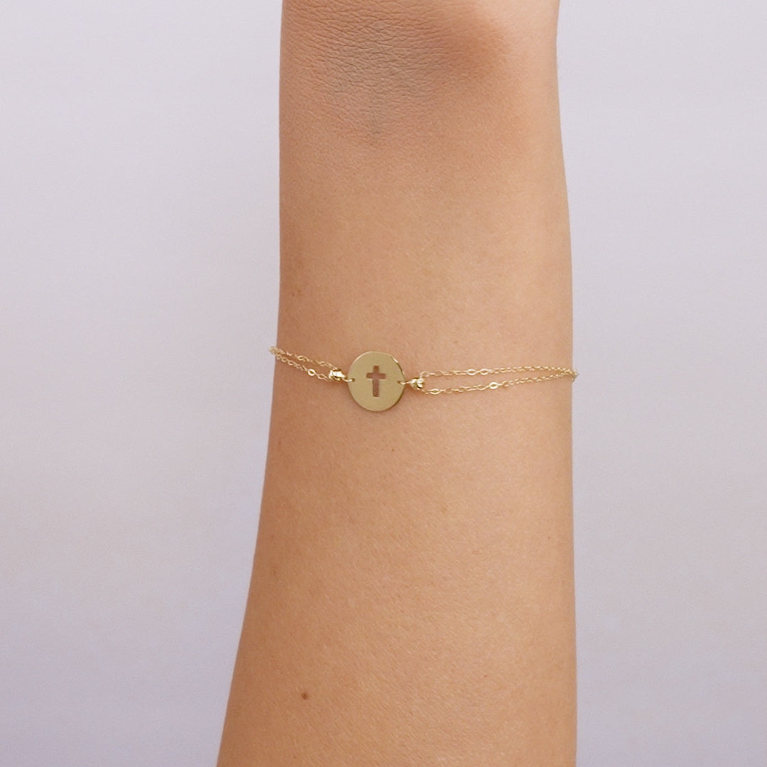 14K solid yellow gold small round disk cross bracelet worn on wrist, delicate design perfect for everyday use.