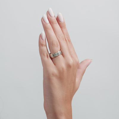 Two tone gold hand engraved men's wedding band worn on a hand with elegantly manicured nails.